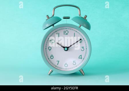 Turquoise classic alarm clock at ten in morning on mint background Stock Photo