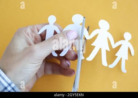 Woman hand cuts paper figures in form of family with scissors closeup Stock Photo