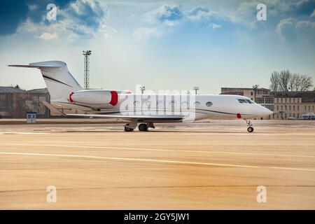 Small white plane at the airport. Runway. Charter flight. Flight on a journey. Fly in a private jet. New beautiful modern transport. Arrival. Stock Photo
