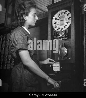 Eine Frau an der Stempeluhr, Deutschland 1940er Jahr. A woman at the attendance clock, Germany 1940s. Stock Photo