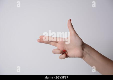 Girl's hand making shooting gun, gesture. hand pistol gesture on isolated white background. Girl hand pointing with two fingers. Stock Photo