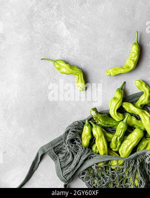 Freshly picked shishito peppers in a cotton mesh bag shot on a gray surface Stock Photo
