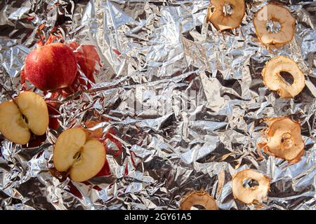 Dried sliced apple chips and fresh apples on the foil background - healthy trendy snacks. Proper nutrition concept. Alternative snacks for party conce Stock Photo