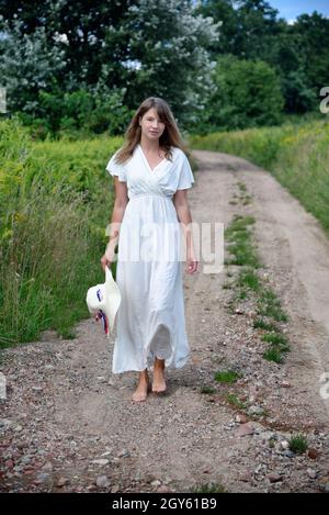 Outdoor photos of young woman in her 30's. Summer season in Poland. Woman on dirt road. Stock Photo