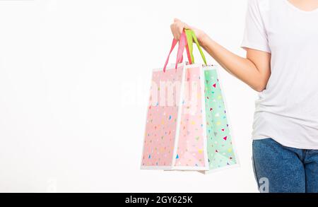 Closeup female holds in hand with multicolor clear empty blank craft paper gift bag, women hand holding colorful shopping bag many packets isolated on Stock Photo