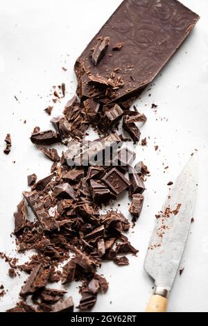 Chopped dark chocolate with a knife on a marble surface Stock Photo