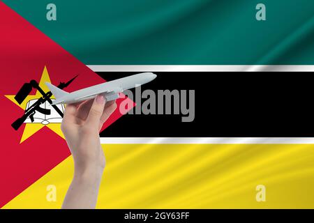 Airplane in hand with national flag of Mozambique. Travel to Mozambique. Stock Photo