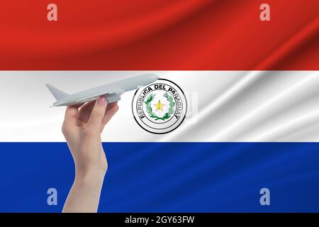 Airplane in hand with national flag of Paraguay. Travel to Paraguay. Stock Photo