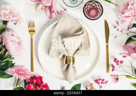 Elegant table setting with floral decor, flat lay. Wedding or festive table setting. Plate and cutlery with pink flowers on white background Stock Photo