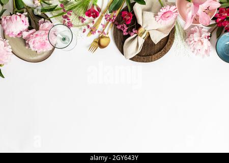 Spring table setting concept - beautiful pink flowers, trendy crockery and cutlery flat lay, copy space Stock Photo