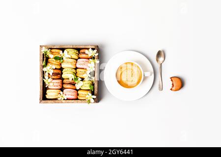 Macaroons in wooden box with spring flowers and cup of coffee flat lay Stock Photo
