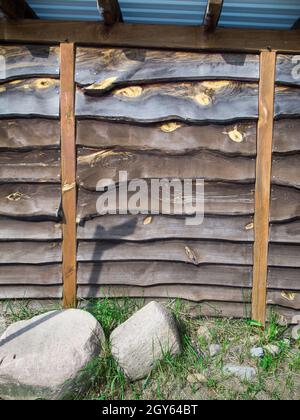 Format-filling view of a wall made of horizontally overlapping and untrimmed boards with two vertical pillars to stabilize the outside area and two fi Stock Photo