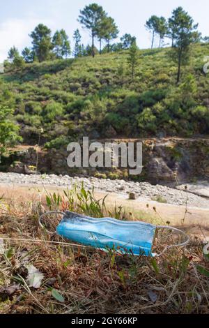 Surgical face mask threw out close to mountain river. Environmental pollution in nature concept Stock Photo