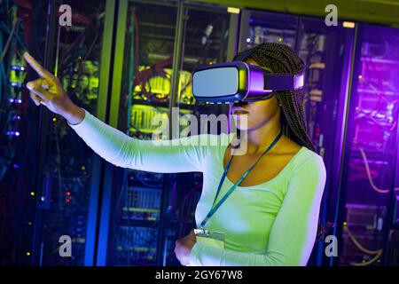 African american female computer technician wearing vr headset and working in server room Stock Photo