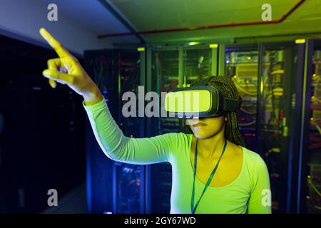 African american female computer technician wearing vr headset and working in server room Stock Photo