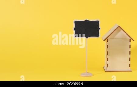 mini wooden house and chalk pointer on a yellow background. Real estate purchase concept, mortgage and home renovation Stock Photo