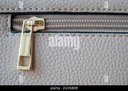Natural or artificial leather texture. Fragment of a beige or powdery bag with a zipper and stitching. Zipper or clasp bag design element. Bovine skin Stock Photo