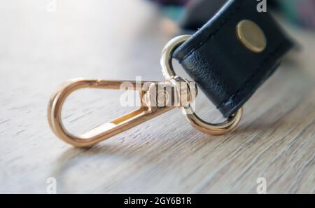 Swivel snap fastener with leather beige bag strap on a wooden background.  Metal carabiner with swivel clip or hook. Small gold fittings close-up in  se Stock Photo - Alamy