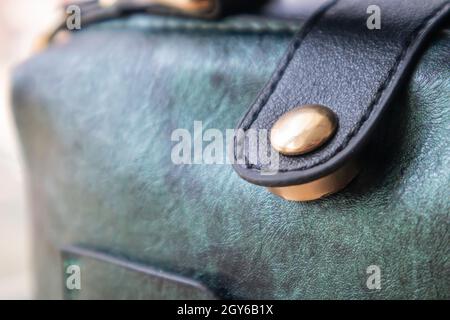 Close-up of gold magnetic button closure open elegant womens fashion green leather shoulder bag. Accessories, detail Stock Photo