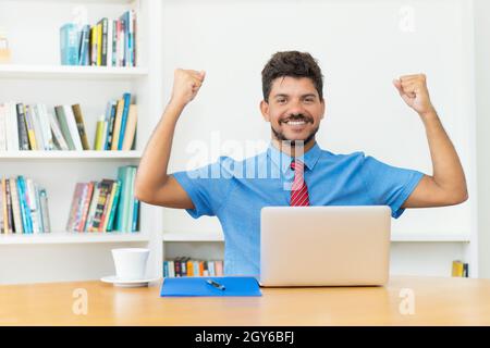 Successfull hispanic male trader at computer at office Stock Photo
