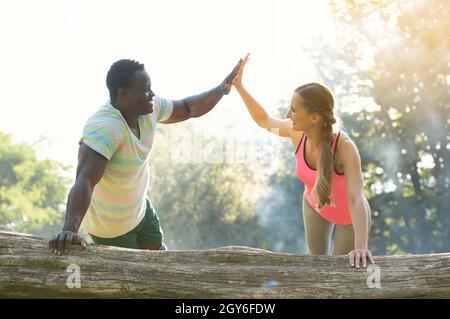 Fitness coach gives some motivation to woman doing push-ups with handshake Stock Photo