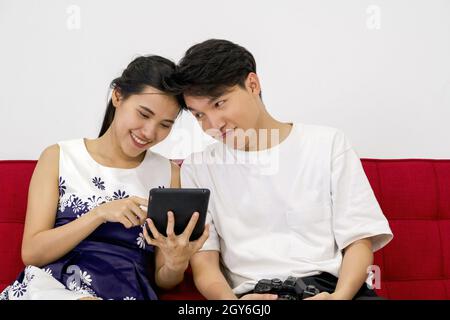 Young lovers spend time together on holidays in the photo studio. The young man allow her girlfriend to view pictures taken on tablet computer screen Stock Photo