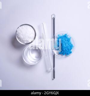 Microcrystalline wax in glass container, Crystal clear liquid in beaker and Copper(II) sulfate in Chemical Watch Glass placed next to the Stirring Rod Stock Photo