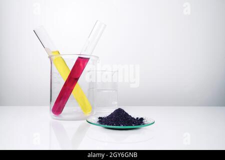 Cosmetic chemicals ingredient on white laboratory table. KMnO4 on chemical watch glass. Potassium Permanganate Liquid and Nickle chloride liquid in te Stock Photo