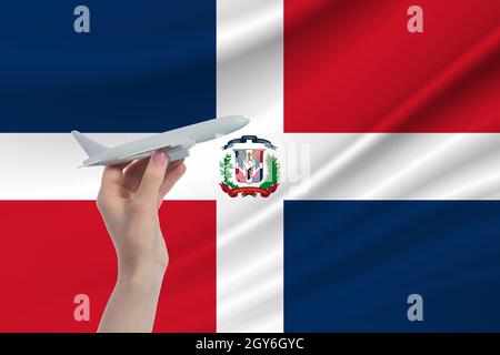 Airplane in hand with national flag of Dominican Republic Travel to Dominican Republic. Stock Photo