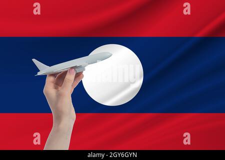 Airplane in hand with national flag of Laos Travel to Laos. Stock Photo