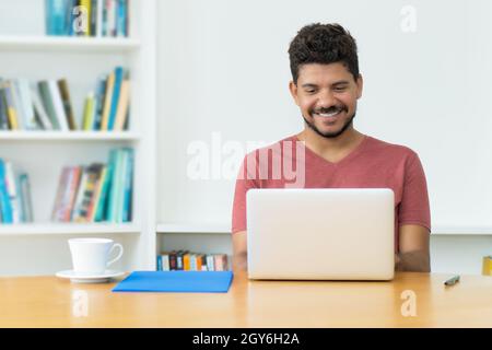 Hispanic mature man with beard at video call at computer indoors at home Stock Photo