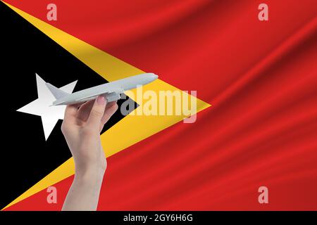 Airplane in hand with national flag of East Timor. Travel to East Timor. Stock Photo