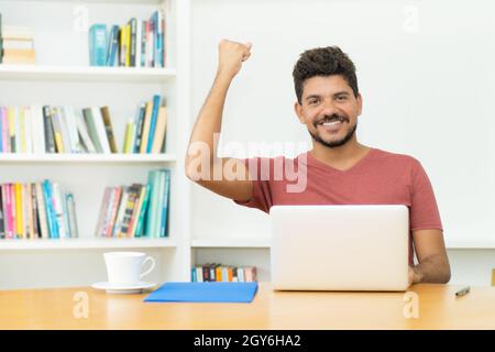 Hispanic mature man with beard shopping online at computer indoors at home Stock Photo