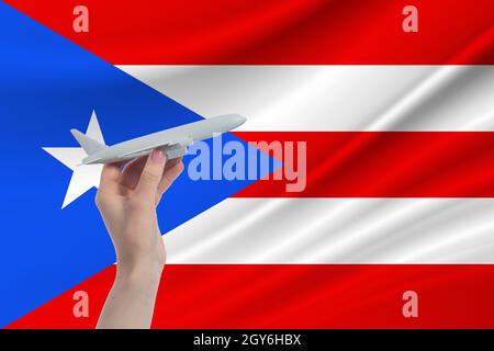 Airplane in hand with national flag of Puerto Rico. Travel to Puerto Rico. Stock Photo