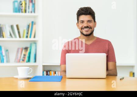 Handsome hispanic mature man with beard working at computer indoors at home Stock Photo