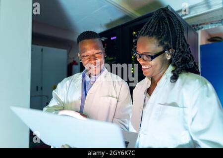 African american computer technicians using laptop working in server room Stock Photo