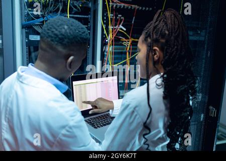 African american computer technicians using laptop working in server room Stock Photo