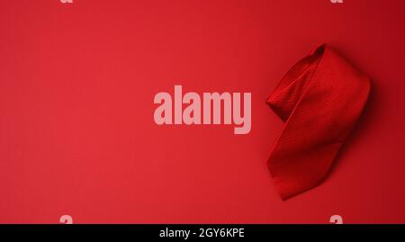 twisted silk red tie on a red background, copy space Stock Photo