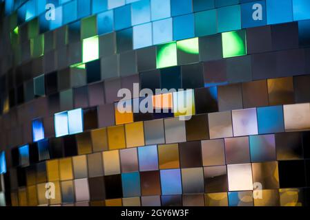 Colorful square metallic tiles on a wall or floor. Blue, green, teal, yellow, orange, purple reflective tile pattern. Shiny tile pattern with purple, Stock Photo
