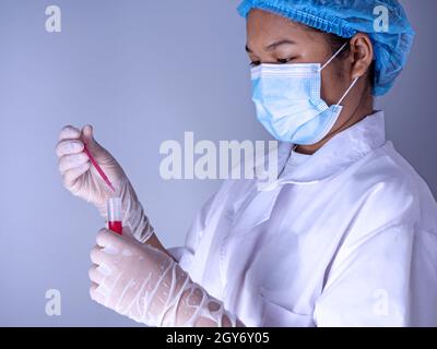 Woman chemist holds flask with red liquid in her hands in chemical laboratory.  Products quality control concept. Stock Photo