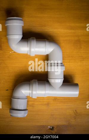 Close up shot of some PVC pipes with connectors, on a wooden background. Stock Photo