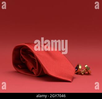twisted silk red tie and cufflinks on a red background, close up Stock Photo