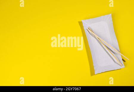 paper rectangular plates wooden chopsticks on yellow background, top view Stock Photo