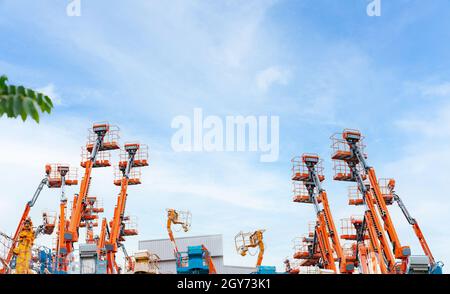Articulated boom lift. Aerial platform lift. Telescopic boom lift against blue sky. Mobile crane parked at parking area for rent. Hydraulic boom lift Stock Photo