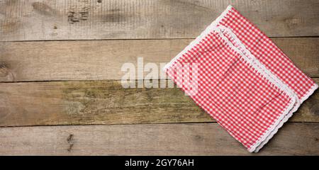 folded red and white cotton kitchen napkin on a wooden gray background, top view Stock Photo