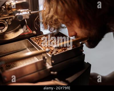 Professional roaster using coffee roasting machine at factory Stock Photo