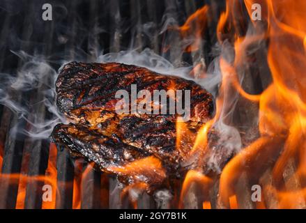 Close up searing and smoking ribeye beef steaks on open fire outdoor grill with cast iron metal grate, high angle view Stock Photo