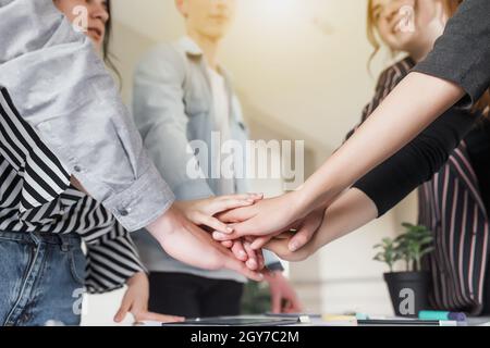 Friendly group of people doing handshake and cross hands. Friendship, agreement, cooperation concept with young teens crossing their hands