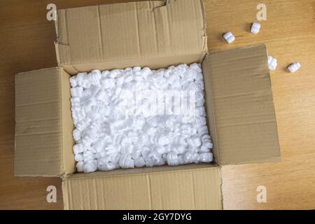 A cardboard box with packing foam top view, Delivery box for fragile product on wooden table copy space Stock Photo