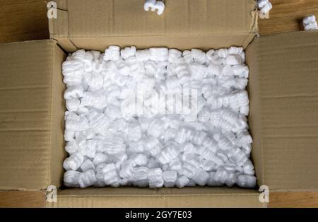 A cardboard box with packing foam top view, Delivery box for fragile product on wooden table copy space Stock Photo